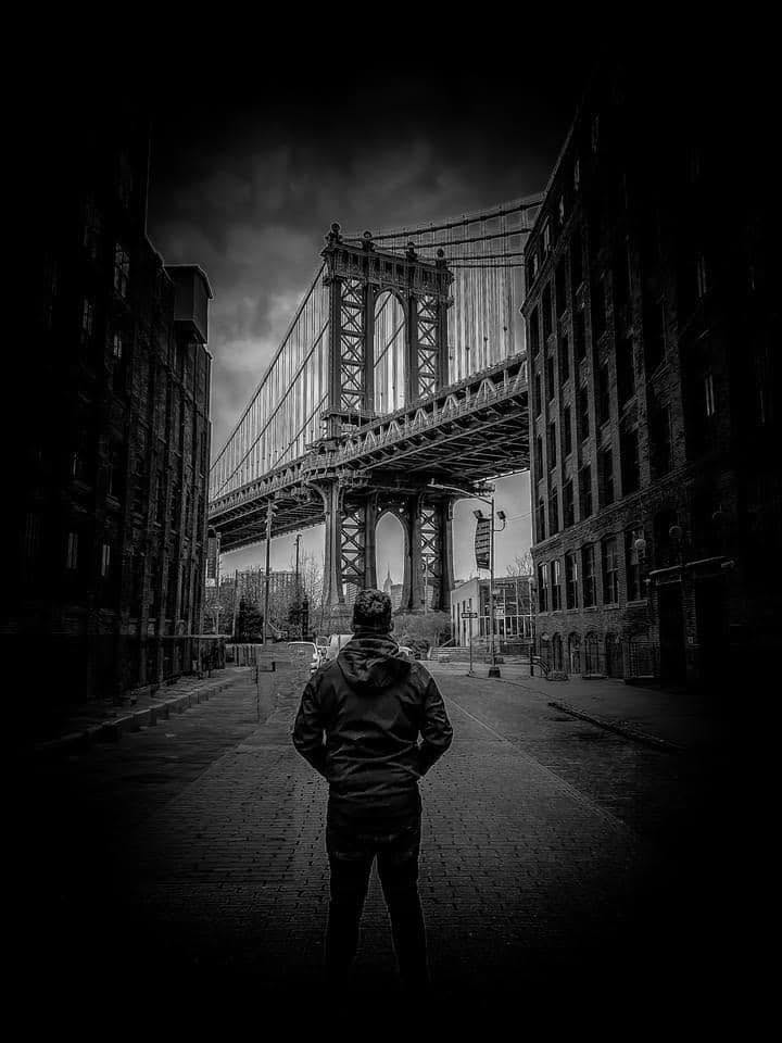Bernard Raffaut standing in an urban street looking toward a bridge